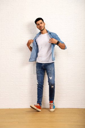 Photo for Smart Guy in white t-shirt with denim jacket giving pose in front of white wall - Royalty Free Image