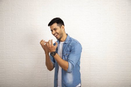 A young good looking man in denim jacket looking at his hands cupped as if holding something