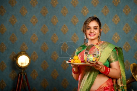 Foto de Imagen de la modelo sonriente usando saree sosteniendo puja thali durante el festival karwa chauth - Imagen libre de derechos
