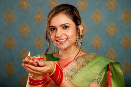 A lovely Indian housewife holding diya while posing for camera