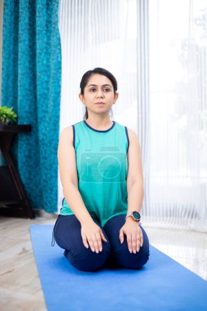Photo for Active woman sitting on mat at home in vajrasana yoga pose - Royalty Free Image