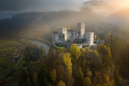 Aerial view of Strecno Castle. Medieval castle standing on high  calcite cliff above the river Vah. Dramatic view of castle in autumn mountain scape, lit by ray of sun. Monuments concept, Slovakia.