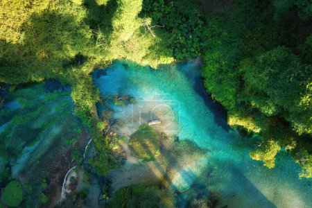 Téléchargez les photos : Eau claire et bleu-vert d'un ruisseau de montagne dans une forêt de chênes et de sycomores, vue panoramique sur une nature pure, aérienne, perpendiculaire. Voyager en Albanie. - en image libre de droit