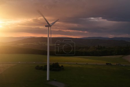Photo for Aerial, scenic view of wind power plant in landscape, illuminated of dramatic, red sunset with stormy clouds. Wind turbine in full load. - Royalty Free Image
