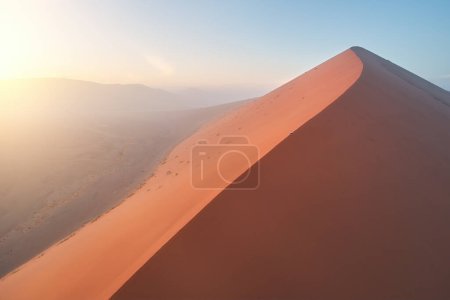 Formen und Schatten riesiger orangefarbener Sanddünen, beleuchtet von der aufgehenden Sonne. Luftaufnahme der Wüstenlandschaft des Namib-Naukluft Nationalparks, Namibia.