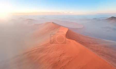 Photo for Shapes and shadows of vast orange sand dunes, illuminated by rising sun. Aerial view of Desertscape of Namib-Naukluft National Park, Namibia. - Royalty Free Image
