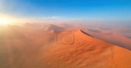 Photo for Shapes and shadows of vast orange sand dunes, illuminated by rising sun. Aerial view of Desertscape of Namib-Naukluft National Park, Namibia. - Royalty Free Image