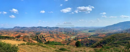 Téléchargez les photos : Le paysage de Madagascar. Rizières en terrasses, villages brun-orange, montagnes en arrière-plan, ciel bleu. Photographie panoramique, Photographie de voyage. - en image libre de droit