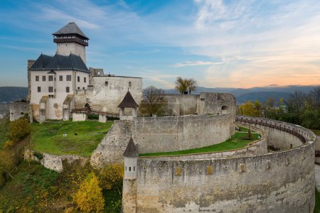 Photo for The mighty Trencin Castle in the colourful autumn landscape. Aerial view of the castle grounds against the blue sky. Travelling around Slovak castles and chateaus. Slovakia, Europe. - Royalty Free Image