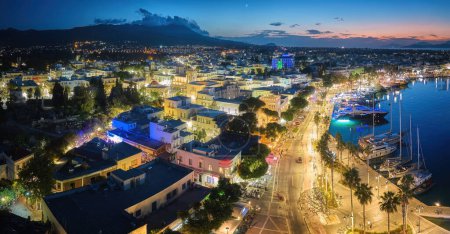 Photo for Port of Kos. Kos Island, Greece. Panoramic, early evening aerial view of the harbour lagoon with yachts and the tourist centre with illuminated promenade. A well-known tourist spot. - Royalty Free Image