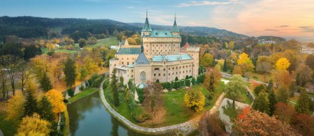 Photo for Bojnice castle. Panoramic aerial view of a neo-gothic romantic fairy-tale castle in a colourful autumn garden. Fortification, towers and water moat. UNESCO  travel concept of the castle and chateau. - Royalty Free Image