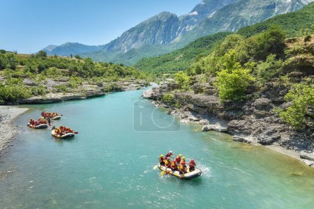 Foto de A group of four yellow rafts floating among the rocks on the crystal clear, blue-green water of Vjosa river, Albania. - Imagen libre de derechos