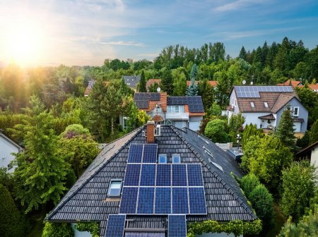 Téléchargez les photos : Vue aérienne des toits des maisons couvertes de panneaux solaires. Maisons familiales dans les jardins, panneaux photovoltaïques sur le toit, été, ciel bleu avec coucher de soleil. Accueil Electricité Génération, vie verte. - en image libre de droit