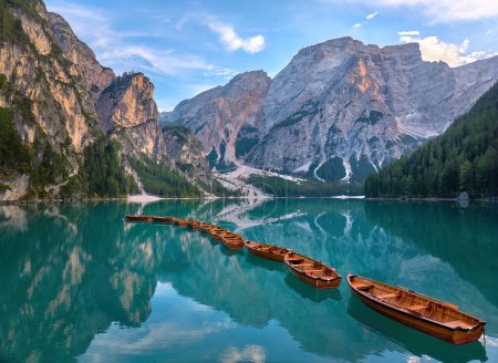 Photo panoramique de Lago di Braies, Pragser Wildsee dans les Dolomites. Vue sur tout le lac vert-bleu à travers des bateaux en bois sur le sommet de la montagne et le soleil couchant.