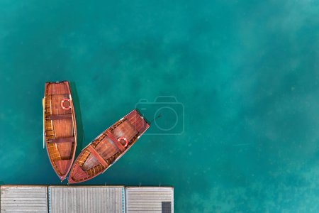 Téléchargez les photos : Vue artistique et perpendiculaire de deux bateaux en bois sur une jetée sur la surface bleu-vert du lac de Braies dans les Dolomites. Idéal pour les projets d'affiches. - en image libre de droit