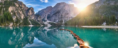 Téléchargez les photos : Photo panoramique de Lago di Braies, Pragser Wildsee dans les Dolomites. Vue sur tout le lac vert-bleu à travers des bateaux en bois sur le sommet de la montagne et le soleil couchant. - en image libre de droit