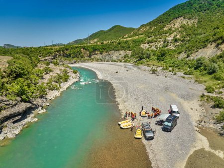 Photo for White water rafting.  Adventure and sport. A yellow raft floating among the rocks on the crystal clear, blue-green water. Perpendicular drone view of the rafters floating on Vjose river, Albania. - Royalty Free Image