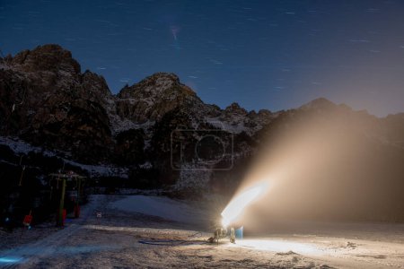 Téléchargez les photos : Cannon tire de la neige sur la piste de ski en action - en image libre de droit