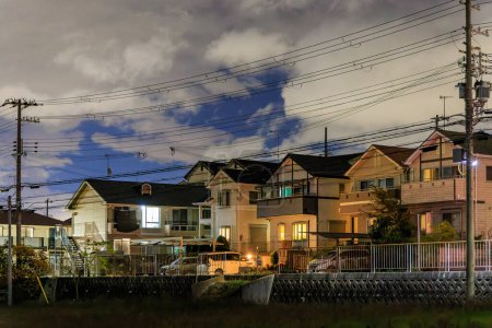 Téléchargez les photos : Maisons de banlieue de deux étages dans une rue calme sous les nuages la nuit. Photo de haute qualité - en image libre de droit