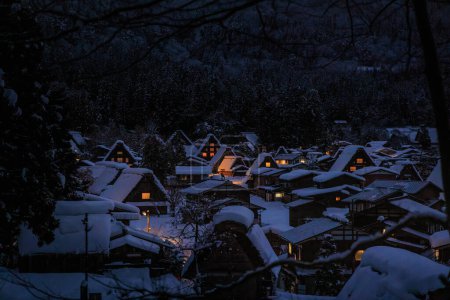 Foto de Las luces de las casas tradicionales brillan en la nieve cubierta Shirakawa-go al atardecer. Foto de alta calidad - Imagen libre de derechos
