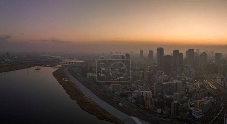 Téléchargez les photos : Hazy sunrise over high rise buildings in sprawling city next to river. High quality photo - en image libre de droit
