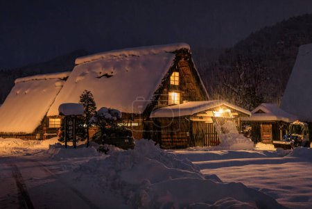 Foto de Snow falls on traditional Japanese gassho-zukuri house at night. High quality photo - Imagen libre de derechos