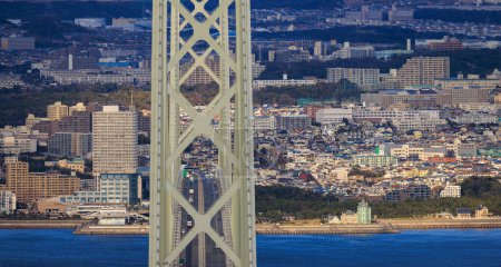 Photo for Akashi Kaikyo suspension bridge with light afternoon traffic and residential apartments in sprawling Maiko - Royalty Free Image