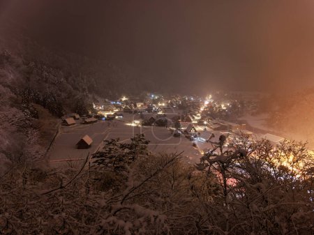 Téléchargez les photos : Enchanted Forest: Shirakawa-go Houses Viewed Through Snowy Misty Trees at Night. High quality photo - en image libre de droit