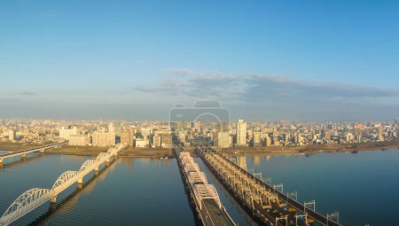 Photo for Vehicle bridge next to train bridge over wide river next to city after sunrise. High quality photo - Royalty Free Image