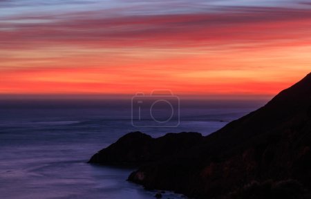 Photo for Red and orange sunset sky and silhouetted coastal mountain. High quality photo - Royalty Free Image