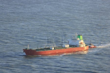 Photo for Cargo Ship and Tugboat Navigate Calm Ocean Waters Entering Port. High quality photo - Royalty Free Image