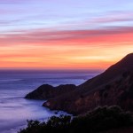Mountain slopes into Pacific Ocean on rugged coast with beautiful sunset. High quality photo