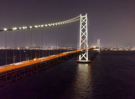 Photo for Lights from traffic blur over long suspension bridge lit at night. High quality photo - Royalty Free Image