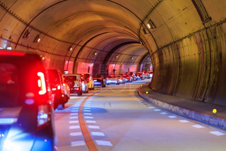 Téléchargez les photos : La ligne de voitures s'est arrêtée dans un grand embouteillage dans un tunnel incurvé. Photo de haute qualité - en image libre de droit