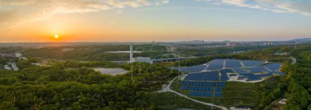 Panoramic aerial view of sunset on horizon and hilltop panels at solar farm. High quality photo