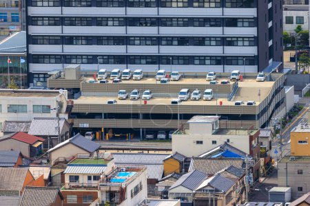 Photo for Sumoto, Japan - May 6, 2023: White cars on parking garage roof by office building and old houses. High quality photo - Royalty Free Image