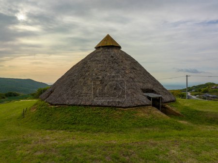 Photo for Historic Jomon thatched roof hut on grassy Awaji Island hill . High quality photo - Royalty Free Image