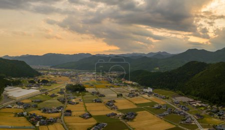 Foto de Vista aérea del cielo del atardecer sobre los campos de trigo dorado y el pueblo rural por las montañas. Foto de alta calidad - Imagen libre de derechos