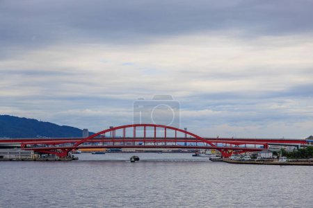 Photo for View from water of tug and barge under red bridge at Kobe Harbor. High quality photo - Royalty Free Image