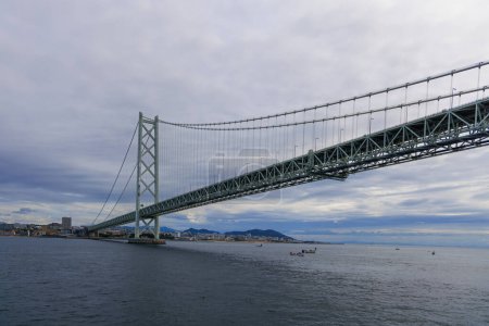 Photo for Akashi suspension bridge with small boats on water under towering span. High quality photo - Royalty Free Image