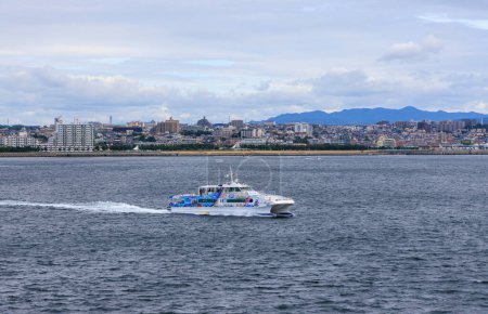 Photo for Akashi, Japan - September 23, 2023: High speed ferry to Awaji Island sails by coastal city. High quality photo - Royalty Free Image