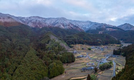 Foto de Campos de arroz en terrazas, casas y montañas nevadas en el paisaje invernal. Foto de alta calidad - Imagen libre de derechos