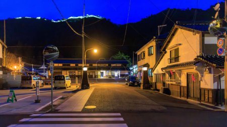 Téléchargez les photos : Takeda, Japon - 28 mars 2023 : Route vide devant la gare avec des lumières de château sur la colline au-dessus. Photo de haute qualité - en image libre de droit