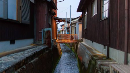 Téléchargez les photos : Passerelle sur le canal entre les maisons traditionnelles japonaises au crépuscule à Takeda, au Japon. Photo de haute qualité - en image libre de droit