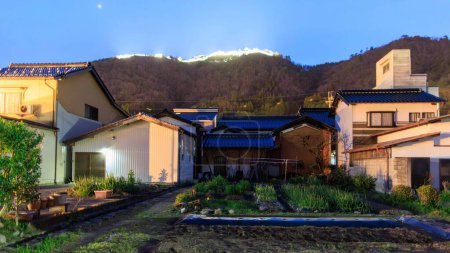 Téléchargez les photos : Petit jardin par des maisons dans un quartier calme avec des lumières du château de Takeda la nuit. Photo de haute qualité - en image libre de droit