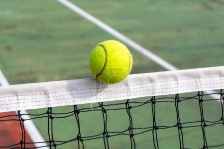 Photo for Close up of tennis ball clips the top of the net. tennis ball hit the net and goes to the other side. Tennis court - Royalty Free Image