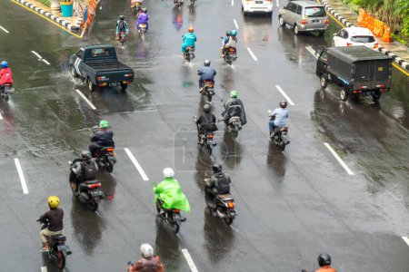 Photo for Surabaya, Indonesia - 18 nov 2021: Cars and motorcycles are passing by at Darmo street in Suarabaya Indonesia. Wet street after the rain - Royalty Free Image