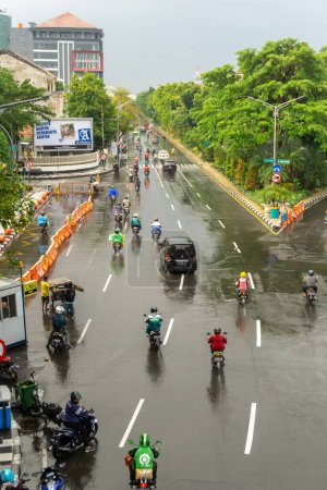 Photo for Surabaya, Indonesia - 18 nov 2021: Cars and motorcycles are passing by at Darmo street in Suarabaya Indonesia. Wet street after the rain - Royalty Free Image
