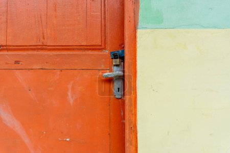 Photo for Rusty metal padlock in orange wooden door. Locked door of abandoned house - Royalty Free Image