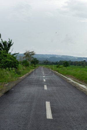 Empty asphalt road with mountain view in the background.  Roadway view in Aceh Besar, Indonesia. 